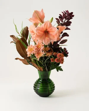 Vinterbukett med röda amaryllis, hypericumbär och vintergrönt – levereras av blomsterbud i Helsingborg.
